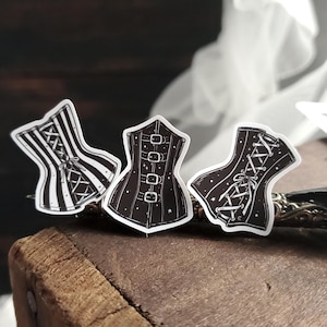 May include: Three black and white corset stickers with different designs. The corsets are decorated with stars and lace.