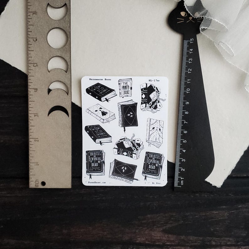 May include: A sheet of black and white stickers featuring illustrations of books with titles like "The Unwritten Library" and "100 Rules for Knowing the Dead".
