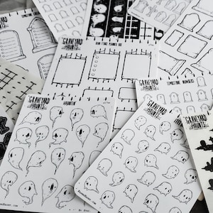 May include: A collection of white sticker sheets featuring black line art. Designs include tombstones, ghosts, and planner elements. The text "GRAVEYARD HAUNTS" is visible on several sheets. The stickers are ideal for Halloween or spooky-themed crafts.