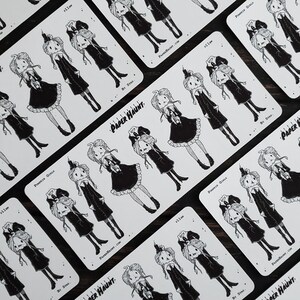 May include: A set of ten black and white stickers featuring illustrations of girls dressed in black dresses with pumpkin heads. The stickers are rectangular and have the text "Paper Haunt" and "Pumpkin Girls" printed on them.
