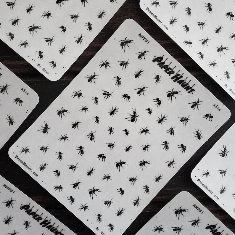 May include: A sheet of black ant stickers with the text "ANTS!" and "PAPER HAUNT" on it. The sheet is white with a subtle texture.