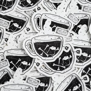 Op de afbeelding: Een verzameling zwart-wit stickers met een theekopje met een schedel en gekruiste botten theezakje. De stickers hebben de tekst "Paper Haunt" erop.