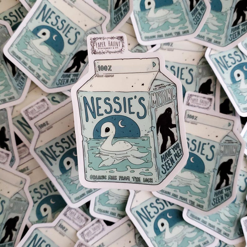 K&ouml;nnte beinhalten: Eine Cartoon-Illustration eines Milchkartons mit blau-wei&szlig;em Design. Der Karton ist mit "Nessie's" beschriftet und zeigt ein Cartoon-Bild des Seeungeheuers von Loch Ness. Der Text "Hast du mich gesehen?" ist auf der Seite des Kartons gedruckt.