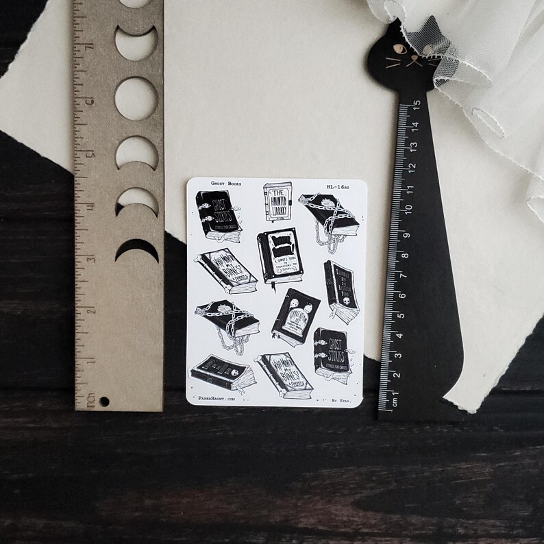 May include: A sheet of stickers featuring black and white illustrations of books with chains and the text "Ghost Stories", "The Time-Worn Library", and "A Scary Good Read".