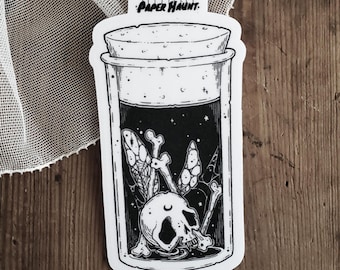Könnte beinhalten: Ein schwarz-weißer Aufkleber mit einem Glas mit Korkdeckel. Im Inneren des Glases befinden sich ein Schädel, Knochen und ein geflügeltes Insekt. Das Glas trägt oben den Text "PAPER HAUNT".