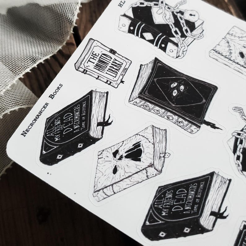 May include: A sheet of stickers featuring black and white illustrations of books with spooky titles like "All My Friends Are Dead" and "The Haunted Library". The stickers are designed in a gothic style with intricate details and are perfect for adding a touch of macabre to your planner, laptop, or water bottle.