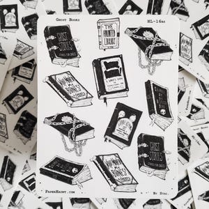 May include: A sheet of stickers featuring black and white illustrations of books with spooky titles like "The Haunted Library", "Who Moved My Bones?", and "Illusions in the Restless Dead". The stickers are part of a collection called "Ghost Books" by Stag.
