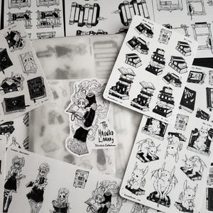 May include: A set of black and white stickers featuring illustrations of a haunted library, including stacks of books, a spooky gargoyle, and a witch reading a book. The stickers are part of a collection called "The Haunted Library Sticker Collection".