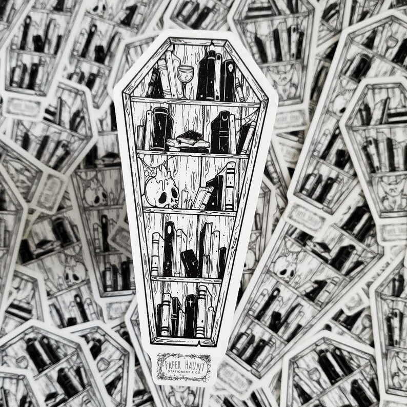 K&ouml;nnte beinhalten: Schwarzwei&szlig;-Illustration eines sargf&ouml;rmigen B&uuml;cherregals, gef&uuml;llt mit B&uuml;chern. Das B&uuml;cherregal hat einen Sch&auml;del und ein Weinglas auf dem obersten Regal. Der Text "PAPER HAUNT STATIONERY & CO." befindet sich am unteren Rand des Bildes.