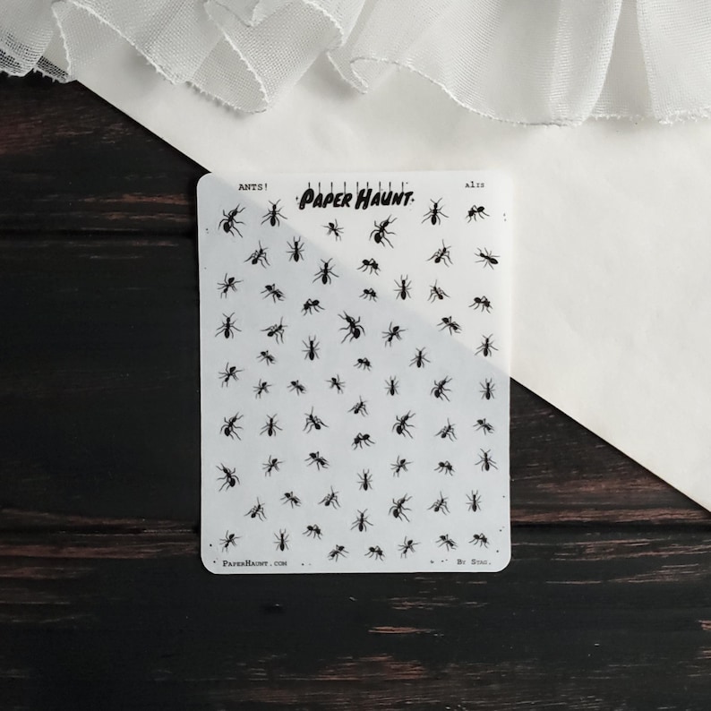 May include: A sheet of clear sticker paper with black ant silhouettes. The sheet is labeled "ANTS!" and "PAPER HAUNT."