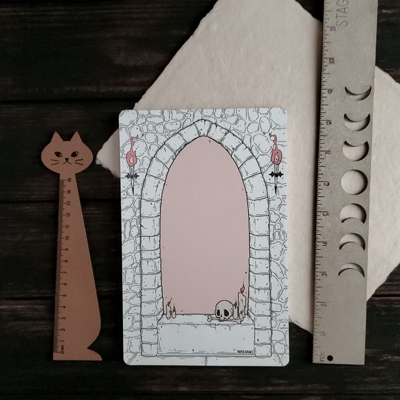 Pode incluir: Uma ilustra&ccedil;&atilde;o em preto e branco de um arco de pedra com um interior rosa. O arco &eacute; decorado com velas e uma caveira. O texto "PATE A LA MODE" &eacute; impresso na parte inferior da ilustra&ccedil;&atilde;o.
