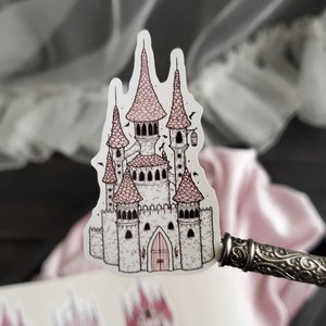 May include: A sticker of a pink and white castle with a detailed design. The castle has multiple towers and a pointed roof. The sticker is on a white background.