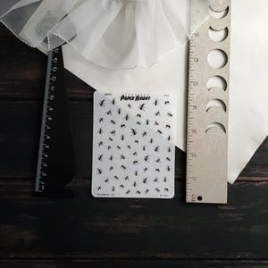 May include: A sheet of clear sticker paper with black ant silhouettes. The sheet is labeled "Paper Haunt" and has the text "Parts 1" and "A1.10".