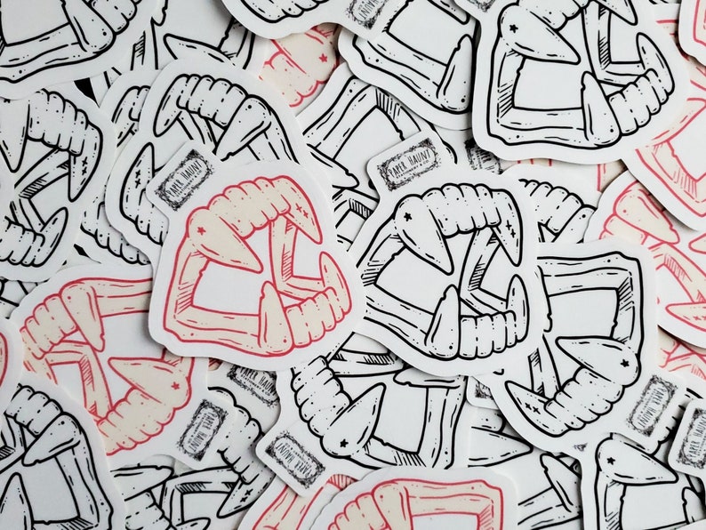May include: A collection of black and white stickers featuring a stylized illustration of a set of fangs. Some of the stickers have a red and white color scheme.