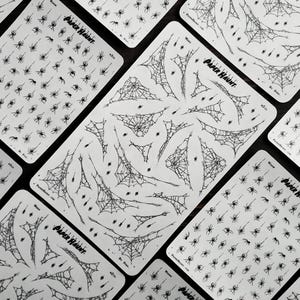 May include: Four sheets of black and white spider web and spider stickers. The stickers are on a white background and feature various sizes of spider webs and spiders. The sheets are labelled "Paper Hunt" and "We Spin..."