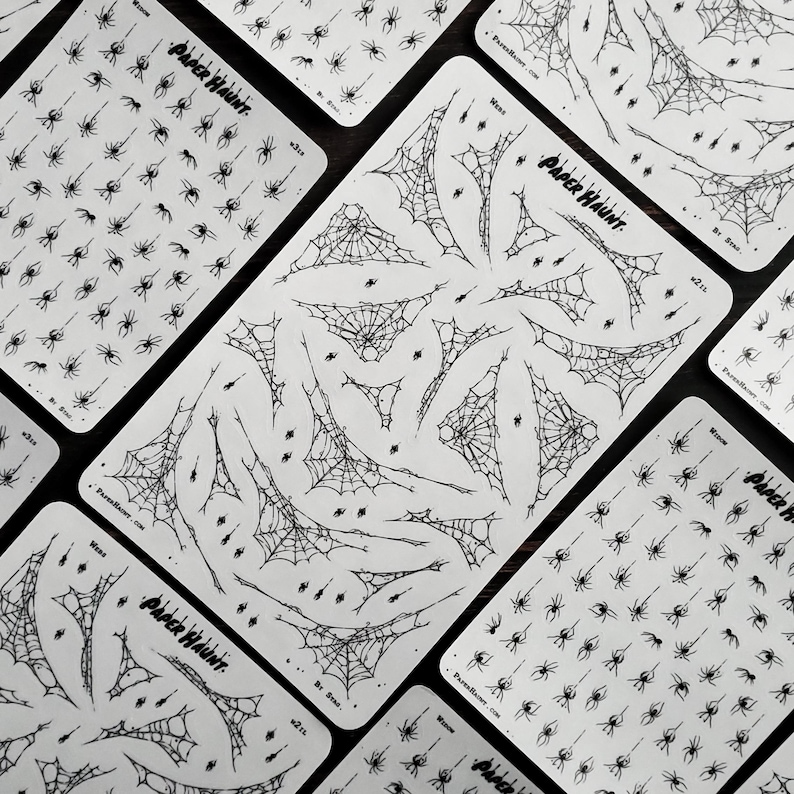 May include: Four sheets of black and white spider web and spider stickers. The stickers are on a white background and feature various sizes of spider webs and spiders. The sheets are labelled "Paper Hunt" and "We Spin..."
