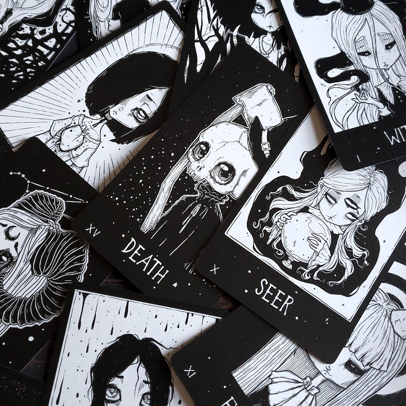 May include: A set of black and white tarot cards with illustrations of various characters. The cards feature a skull with an axe, a woman with a crystal ball, and a woman with a star. The cards are labeled with the names of the tarot cards, such as "Death" and "Seer".