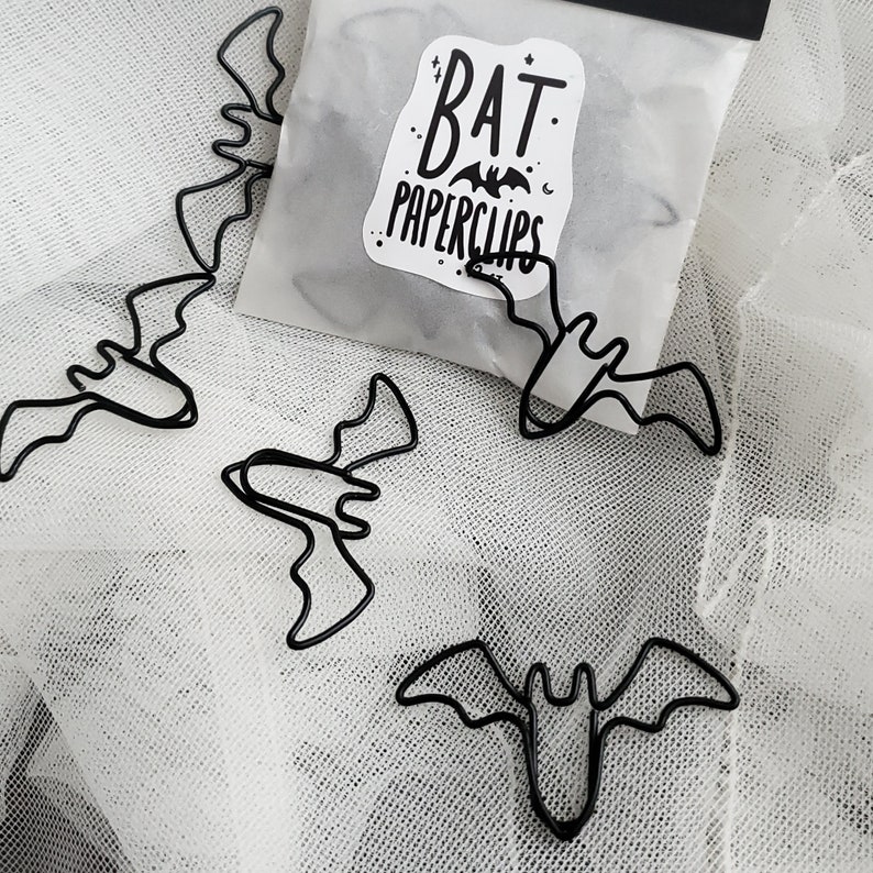 May include: A bag of black metal bat-shaped paperclips. The bag has a sticker on it that says "Bat Paperclips".