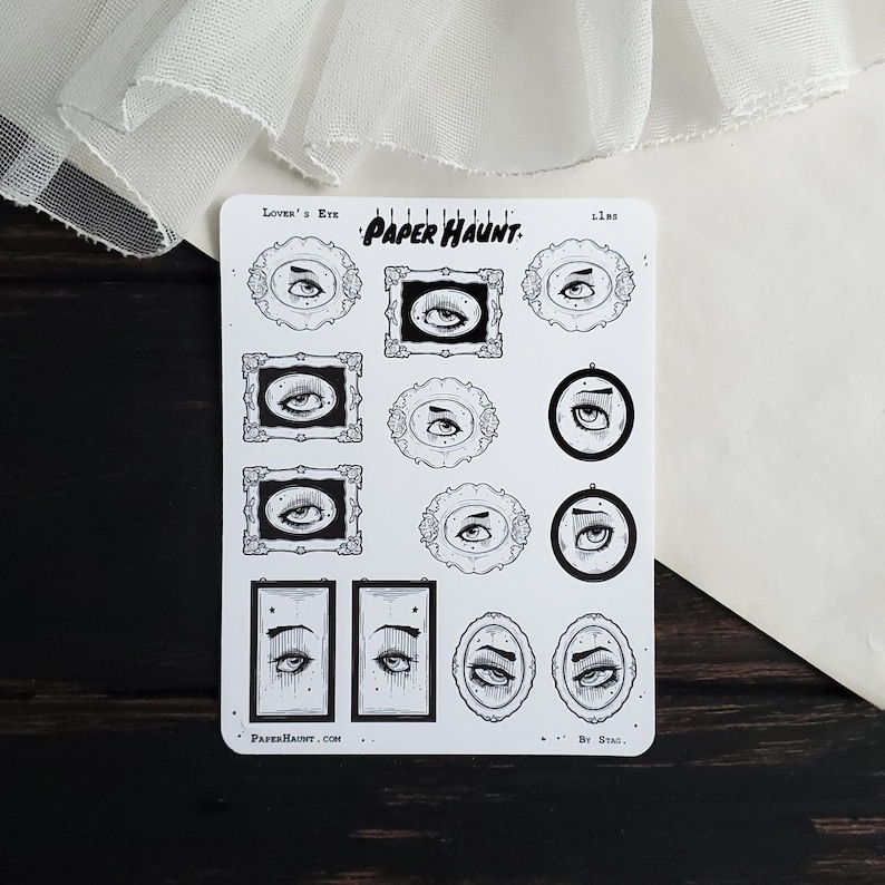 May include: A sheet of stickers featuring various black and white illustrations of eyes in different frames. The stickers are labeled "Lover's Eye" and "Paper Haunt."