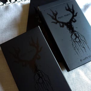 May include: Two black playing card decks with a black and white illustration of a deer head with antlers on the front. The text "Mystic Minty" is printed on the front of the deck. The text "By White Star" is printed on the bottom right corner of the deck.