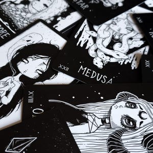 May include: Black and white tarot cards with illustrations of women and mythical creatures. The cards feature Roman numeral numbers and titles such as "Medusa" and "The Star".