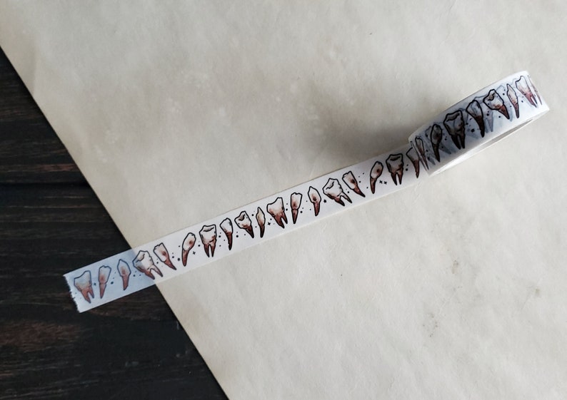 May include: White washi tape with a repeating pattern of brown teeth.