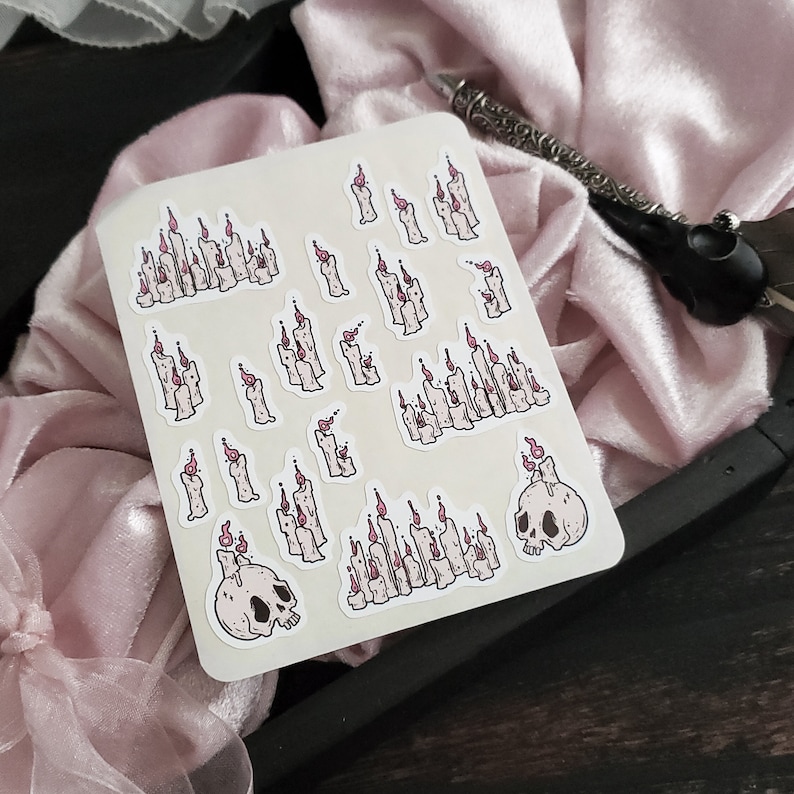 May include: A sheet of stickers featuring various illustrations of candles and skulls. The candles are depicted in a variety of sizes and shapes, with some featuring flames and others without. The skulls are depicted in a simple, cartoon style.