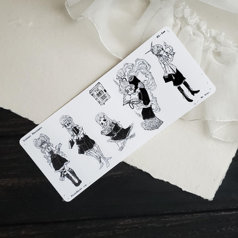 May include: A sheet of black and white stickers featuring illustrations of girls reading books. The stickers include the text "Library Ramble" and "The Unread Book".