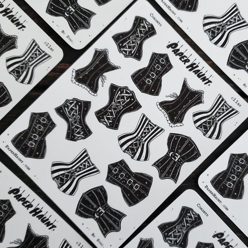 May include: A sheet of black and white stickers featuring various corset designs. The stickers are printed on white paper and have a glossy finish. The text "Paper Haunt" and "Corsets" is printed on the sheet.