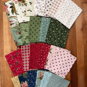 May include: A collection of folded fabric squares featuring various holiday-themed patterns including poinsettias, holly leaves, plaid, stars, and floral swirls in a color palette of red, green, white, gold, blue, and light pink.