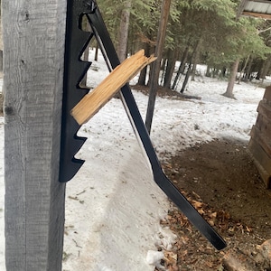 May include: A black metal log splitting wedge mounted on a wooden post. A piece of wood is wedged in the splitting wedge.