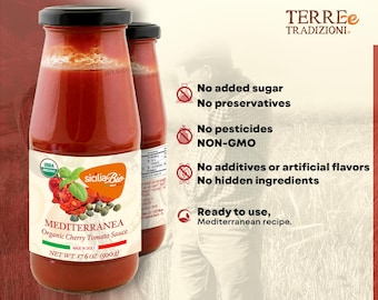 May include: A glass jar of red organic cherry tomato sauce with a white label that reads "MEDITERRANEA Organic Cherry Tomato Sauce" and "sicilia Bio". The label also includes the USDA Organic seal. The jar is sitting on a wooden surface. The background is a blurred image of a field of wheat.