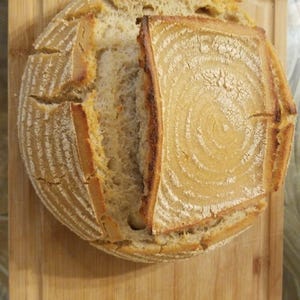 May include: A freshly baked loaf of sourdough bread with a crispy crust and a soft, airy interior. The bread is sliced open, revealing the intricate patterns of the dough.