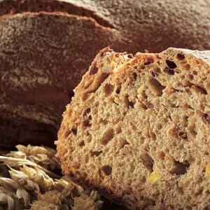 May include: A close-up of a sliced loaf of brown bread with a grainy texture. The bread is fresh and has a golden brown crust.