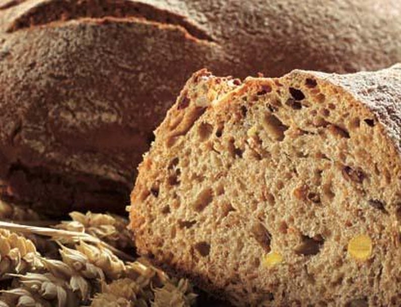 May include: A close-up of a sliced loaf of brown bread with a grainy texture. The bread is fresh and has a golden brown crust.