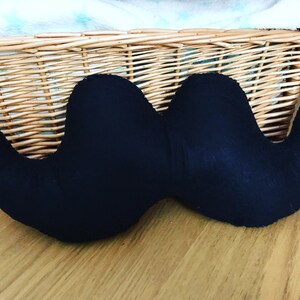 Pu&ograve; includere: Un cuscino a forma di baffi in tessuto nero. Il cuscino &egrave; a forma di baffi ed &egrave; realizzato in un tessuto morbido e peluche.