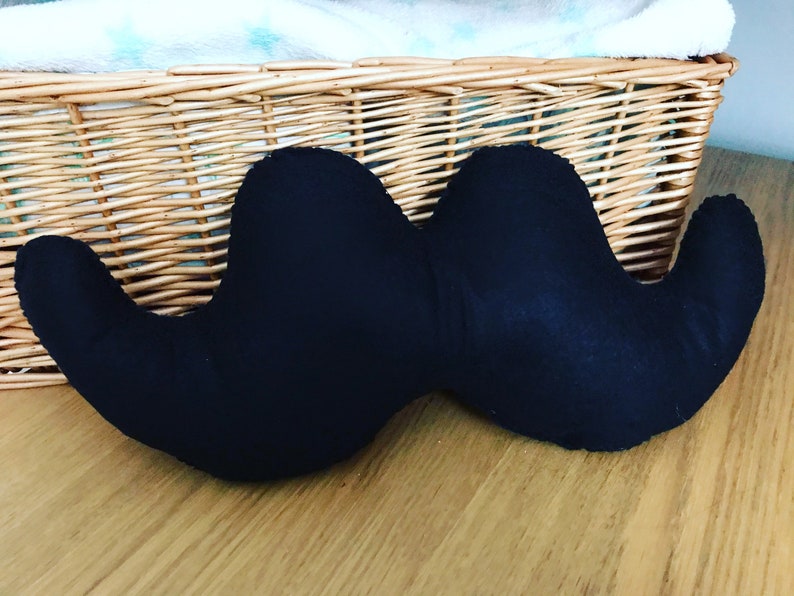 Pu&ograve; includere: Un cuscino a forma di baffi in tessuto nero. Il cuscino &egrave; a forma di baffi ed &egrave; realizzato in un tessuto morbido e peluche.
