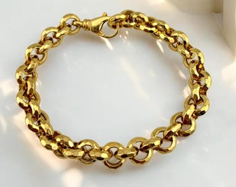 May include: A gold-colored bracelet with a textured, hammered chain link design. The bracelet features a lobster clasp closure. The links are oval-shaped and have a faceted surface, catching the light. The bracelet is approximately 7.5 inches in length.