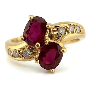 May include: A gold ring featuring three oval-cut rubies and small diamonds. The rubies are a deep red color, and the diamonds are clear. The ring has a classic, elegant design, perfect for a special occasion.