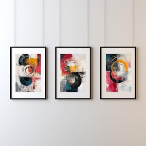 May include: Three framed abstract art prints. Each print features a composition of overlapping circles and geometric shapes in black, yellow, red, and teal. The artwork is set against a white background, framed in black.