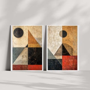 May include: Two abstract geometric paintings in a minimalist style. The paintings are framed in white and feature a combination of geometric shapes in shades of brown, gray, black, and red. The paintings are set against a white background.
