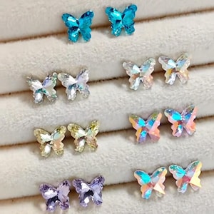 May include: A collection of butterfly-shaped crystal embellishments in various colors. The assortment includes pairs of blue, clear, yellow, iridescent, and purple butterflies. These decorative crystals are ideal for crafts and jewelry making.