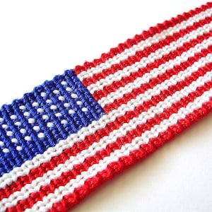 May include: A woven friendship bracelet with red, white, and blue stripes, resembling the American flag. The bracelet features a blue section with white dots, representing the stars.