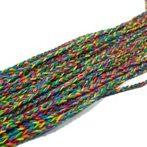 Puede incluir: Primer plano de un cordón trenzado hecho de múltiples hebras de hilo de colores. El cordón está tejido en un patrón de espiga y presenta tonos de rojo, naranja, amarillo, verde, azul, morado y rosa.