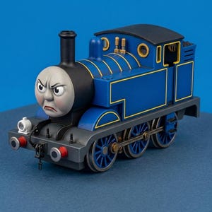 May include: A blue toy steam locomotive featuring a grey face with an angry expression, black smokestack, and yellow trim. The train has six blue wheels, a small white front lamp, and red buffers on the front bumper, set against a blue background.