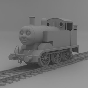 Op de afbeelding: Een grijze speelgoedtrein met een lachend gezicht, geplaatst op een grijs spoor. De trein heeft een cilindrisch lichaam, een kleine schoorsteen en zichtbare wielen. Het ontwerp doet denken aan een klassiek kinderspeelgoed.