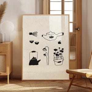以下が含まれることがあります： お茶に関連するアイテムの黒い線画が描かれた、額入りのアートプリント。アートワークには、ティーポット、ティーカップ、泡立て器、ケトル、鉢植えの植物が含まれています。背景はニュートラルなベージュ色です。