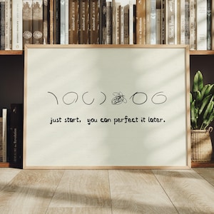 May include: A framed rectangular print on a light cream background featuring black line art of a series of circles and a scribble, with the text "just start, you can perfect it later." printed in a simple black sans-serif font.