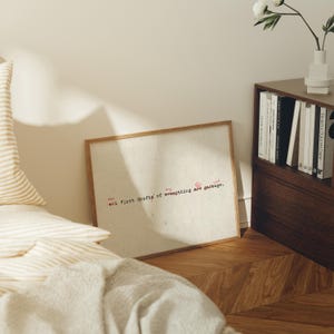 Puede incluir: Un marco de madera que contiene una impresi&oacute;n con el texto "the +1 first drafts of everything are garbage" en rojo y negro. La impresi&oacute;n tiene un fondo beige claro. El marco est&aacute; apoyado contra una pared.