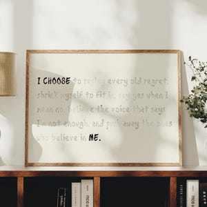 May include: A rectangular framed wall art piece featuring a light beige background with black text that reads: I CHOOSE to replay every old regret, shrink myself to fit in, say yes when I mean no, believe the voice that says I'm not enough, and push away the ones who believe in ME.